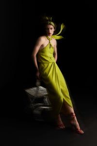 woman leaning against chair in lime green halterneck evening dress