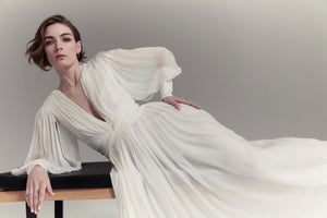 Bride lying on bench wearing a long sleeve silk wedding dress