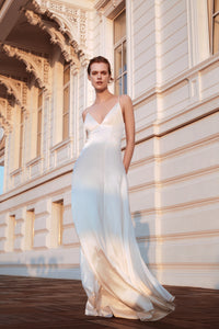 bride standing in front of building wearing white silk slip wedding gown