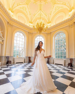 Bride standing in ballroom wearing a lace wedding dress