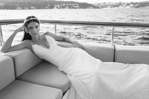 bride lying down on boat wearing a lace wedding dress